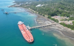 Kapal kargo bersandar di dermaga pesisir berhutan, ilustrasi kota pelabuhan tujuan mobil travel Medan-Dumai