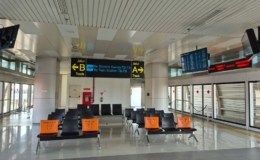 Ruang tunggu bandara dengan kursi dan layar informasi, ilustrasi mobil travel Medan antar jemput Kualanamu